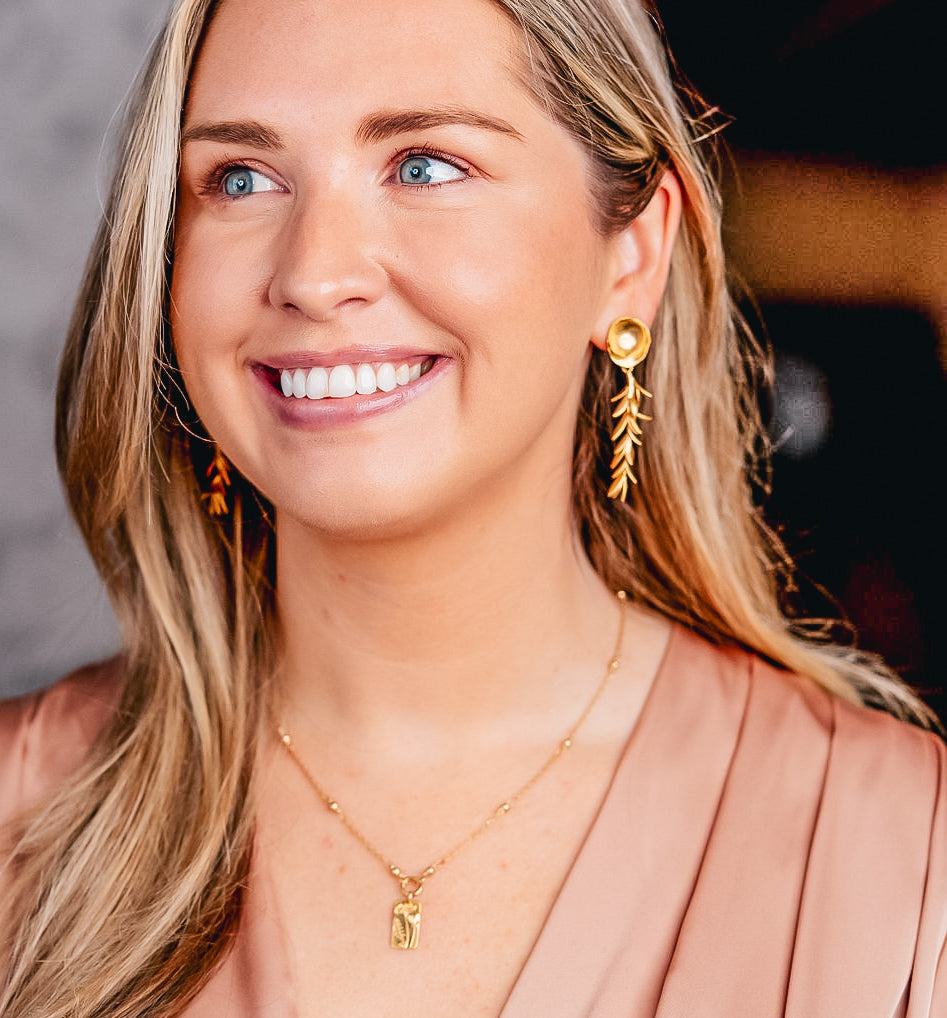 A model wearing a gold branch dangle earring