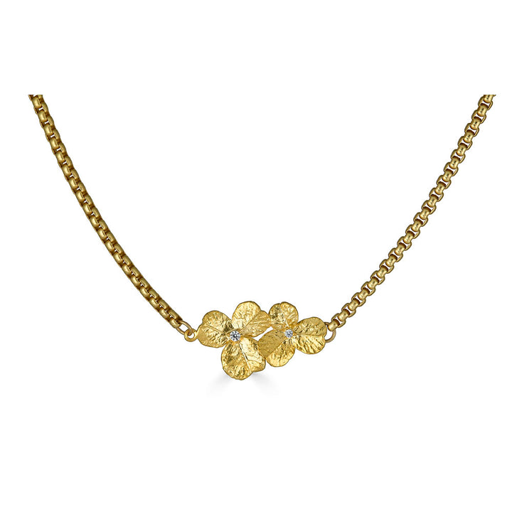 a bar necklace with a gold clover connector