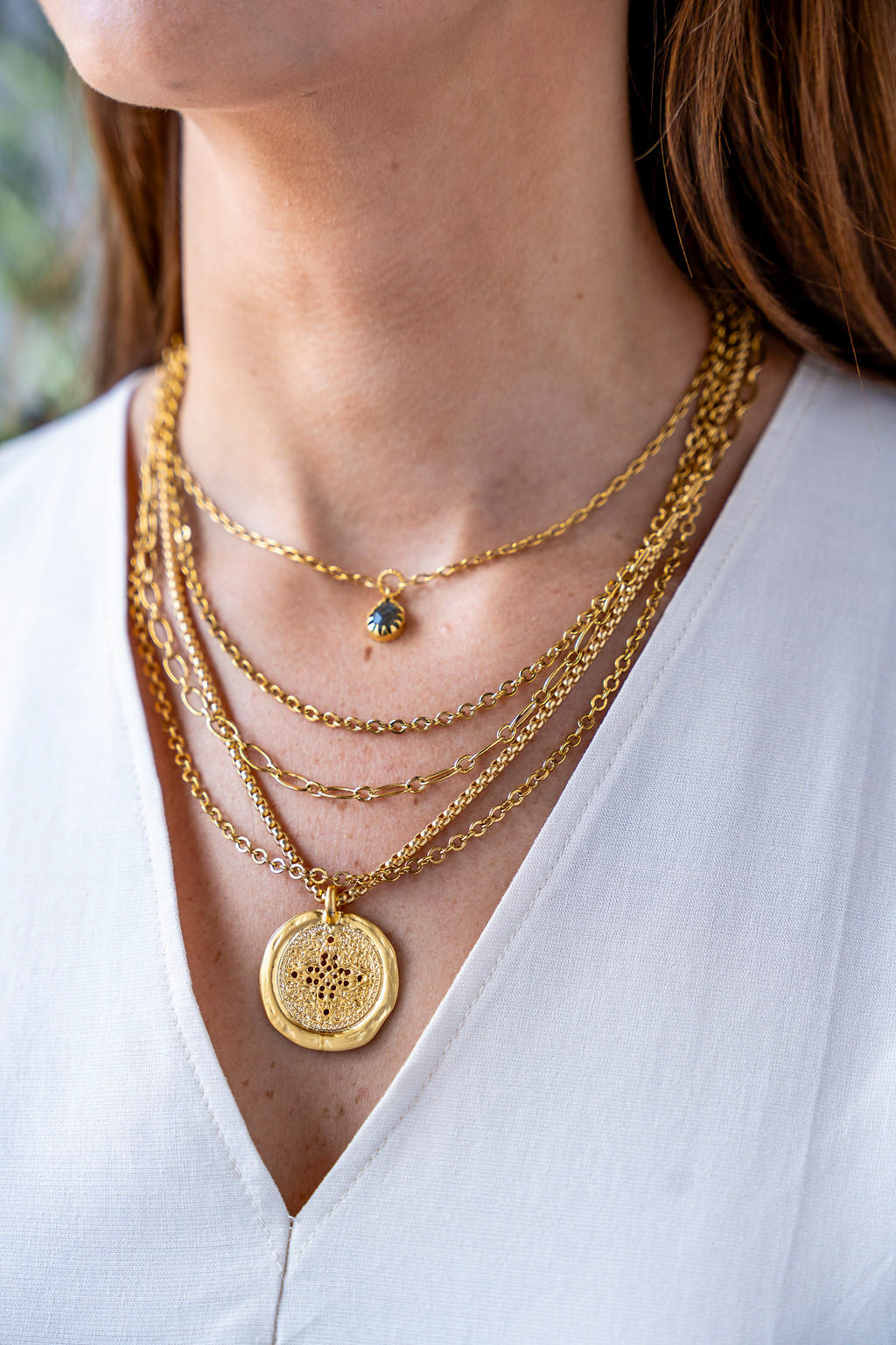 Matte gold coin necklace with filigree-etched round pendant on a rounded box chain.