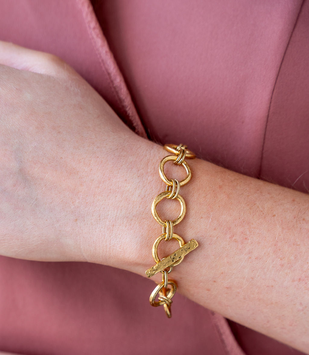 Gold bracelet featuring organic sculpted circle links with twisted rope details and a hammered toggle clasp.