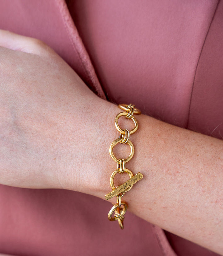 Gold bracelet featuring organic sculpted circle links with twisted rope details and a hammered toggle clasp.