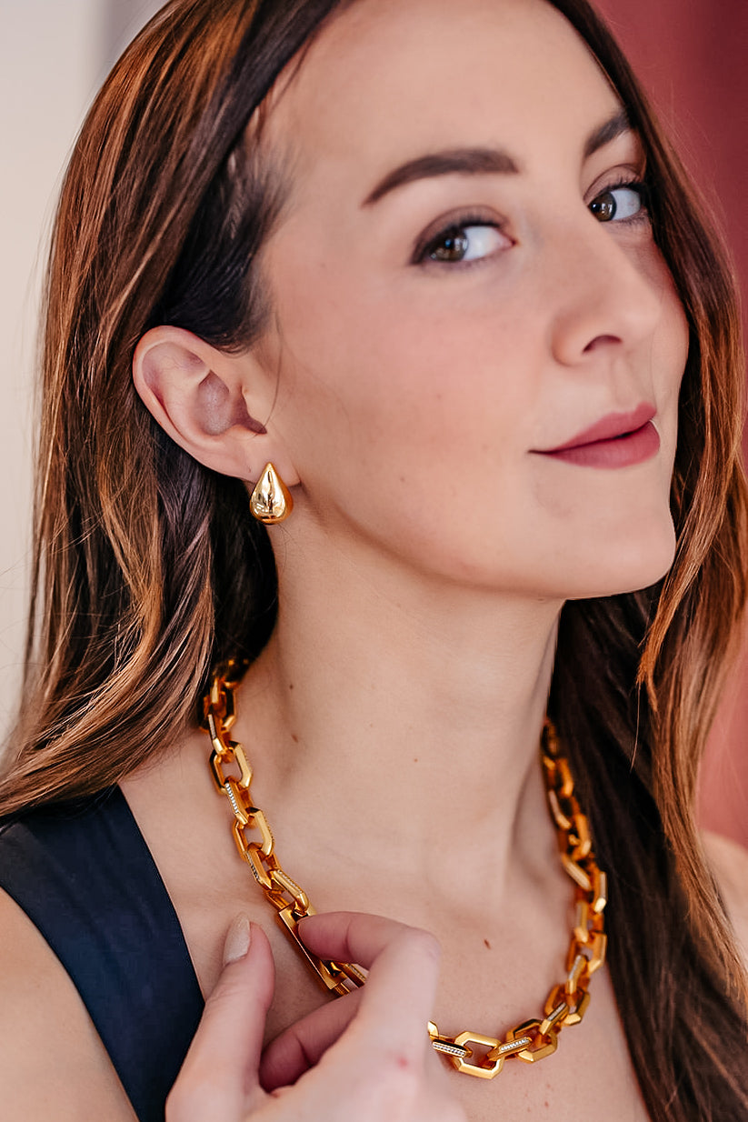 A model wearing A pair of gold teardrop earrings.
