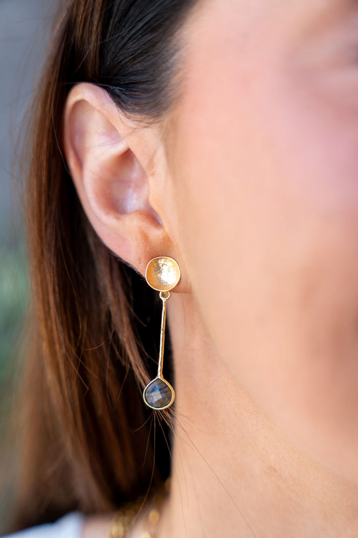 Gold drop earrings with hammered disc tops, textured vertical bars, and teardrop labradorite stones at the base.