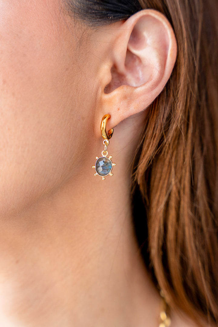 Gold hoop earrings with hammered finish and fixed oval labradorite charm framed by rounded prongs.