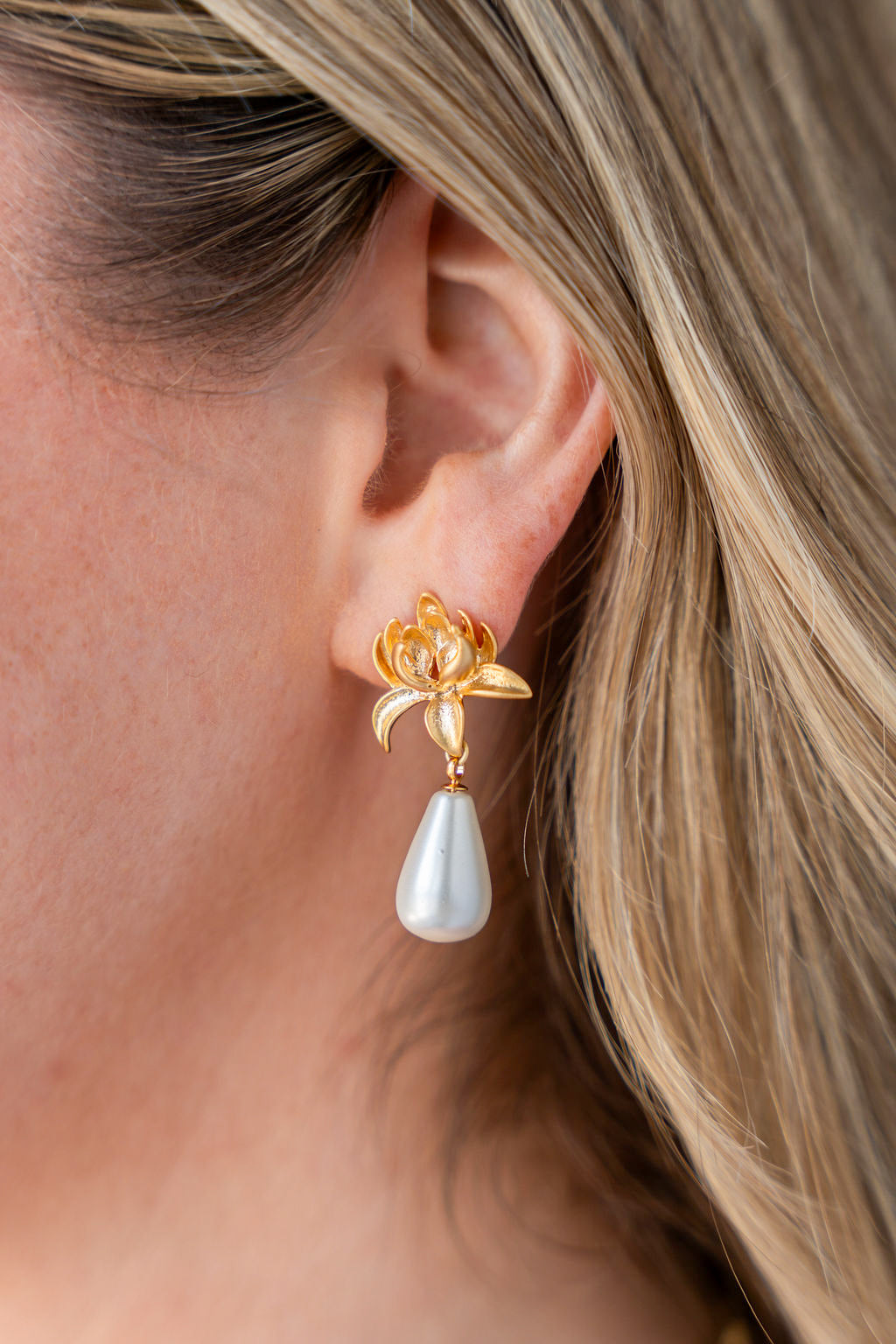 Gold lily-shaped earrings with teardrop silver shell pearl drops and post back closures.