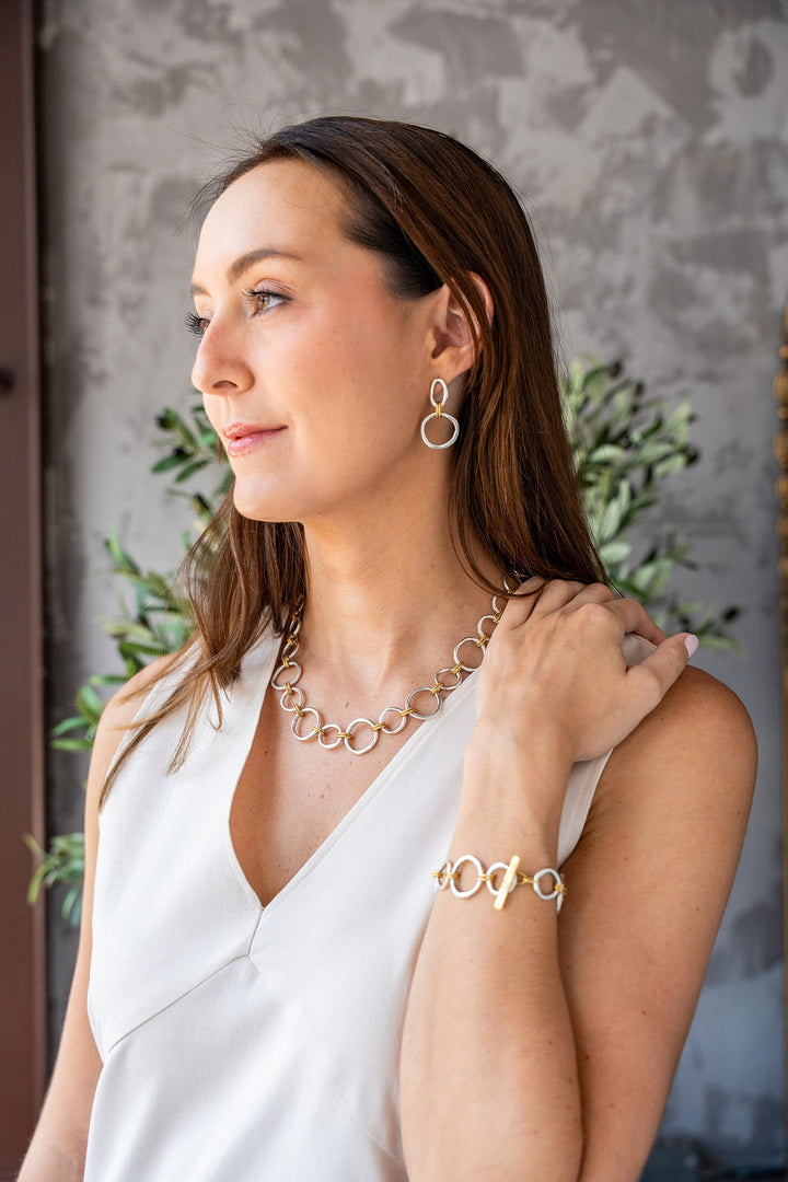Mixed metal bracelet featuring brushed silver sculpted circle links with gold rope accents and a toggle clasp.