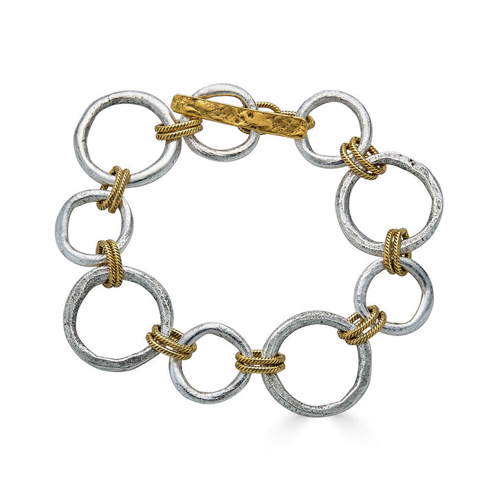 Mixed metal bracelet featuring brushed silver sculpted circle links with gold rope accents and a toggle clasp.