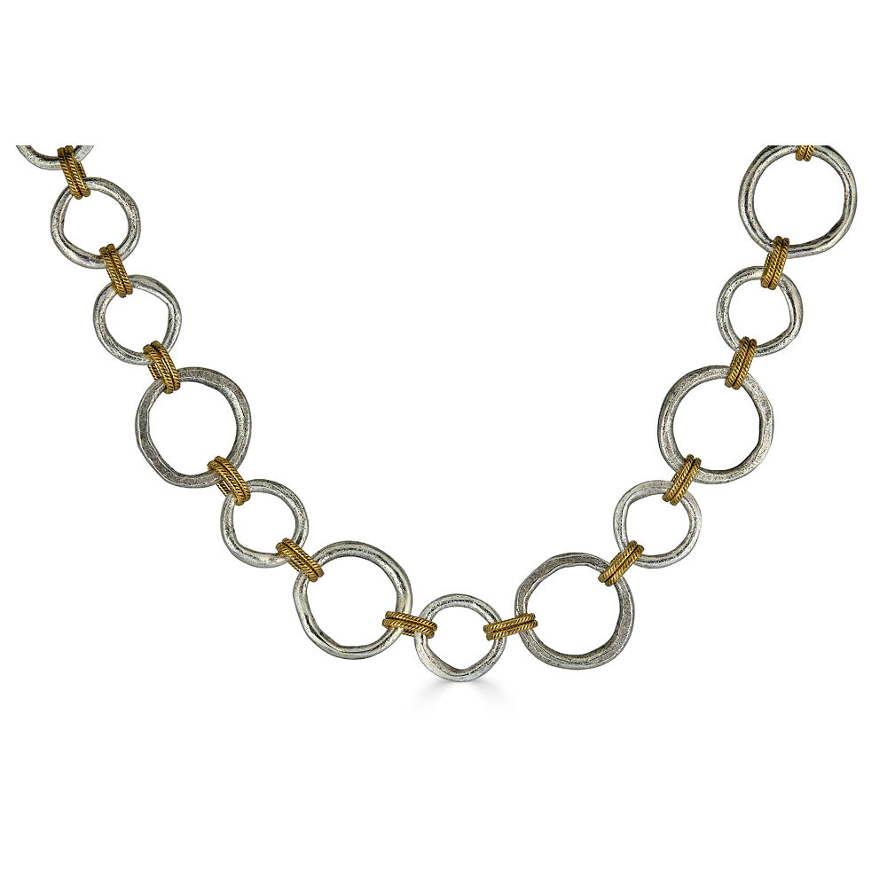 Mixed metal necklace with matte silver and gold sculpted circle links, toggle clasp, and rope-textured accents styled multiple ways.