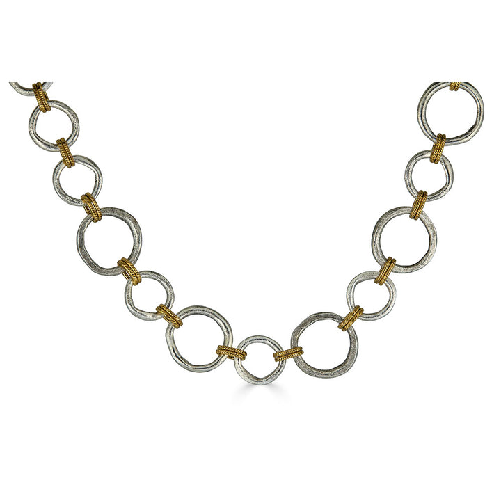 Mixed metal necklace with matte silver and gold sculpted circle links, toggle clasp, and rope-textured accents styled multiple ways.