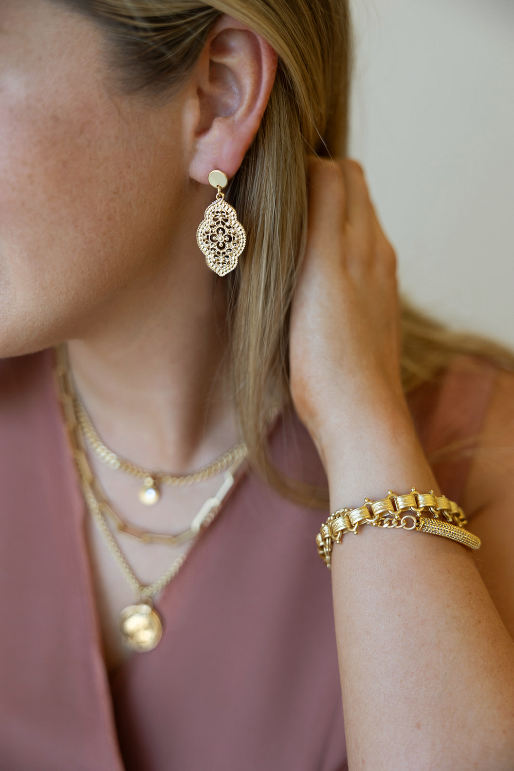 An oval lace earring on a gold post