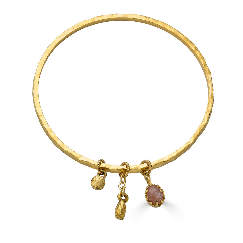 Gold bangle bracelet with peach moonstone, teardrop, and coin charms.