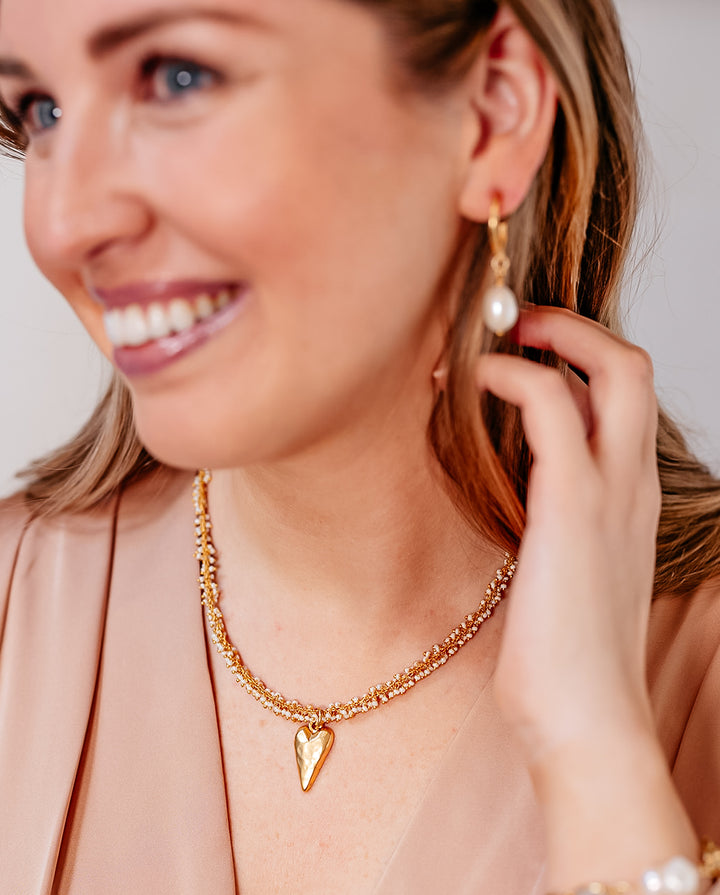 A model wearing A seed pearl drizzle necklace with a hammered heart pendant