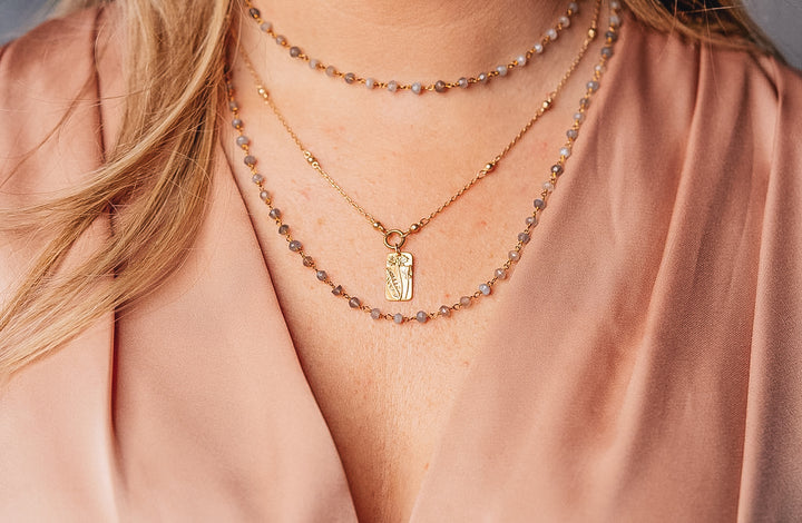 a model wearing a rectangle flower necklace on a delicate chain