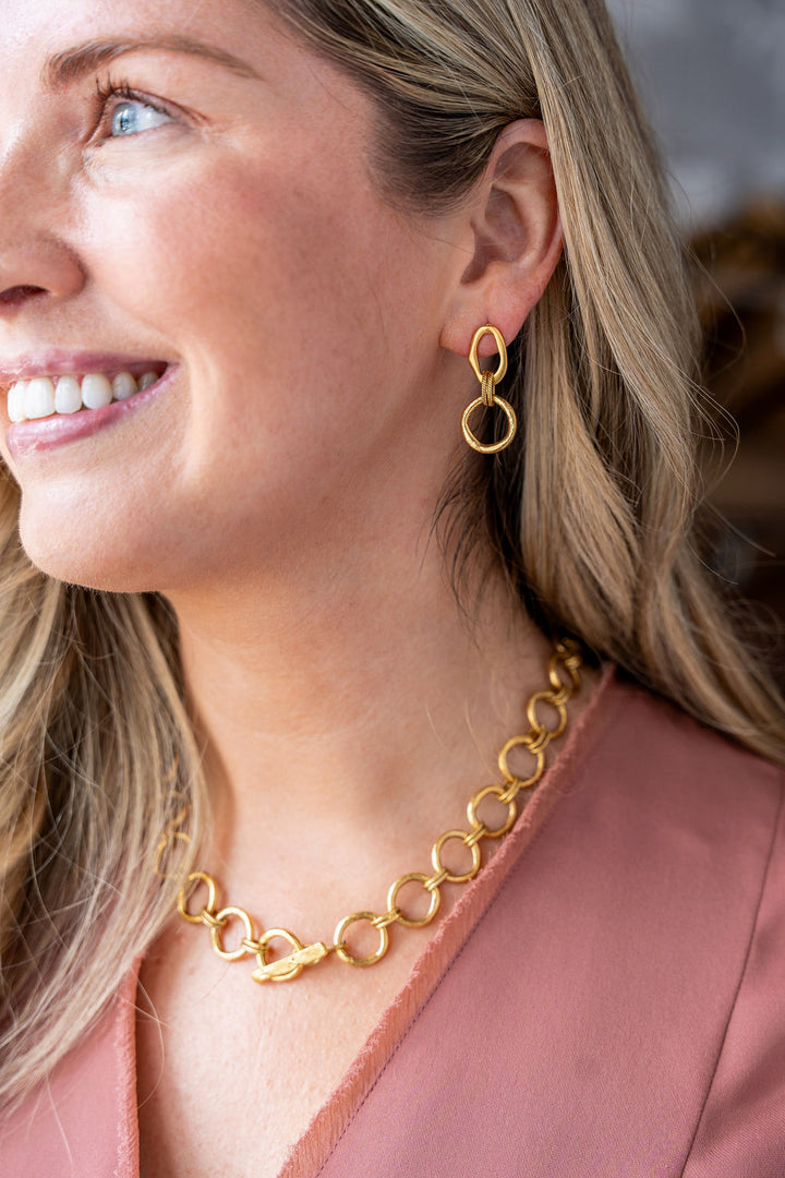 Gold drop earrings with two linked sculpted circles and a textured rope connector.