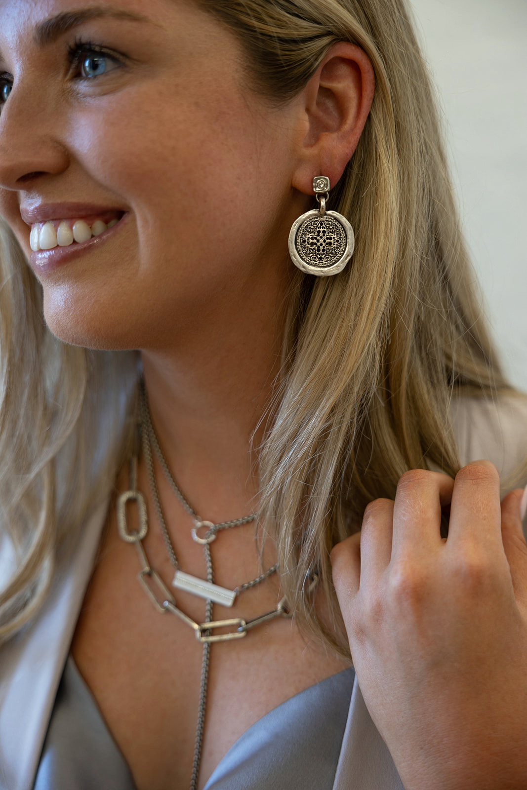 A silver filagree coin dangle earring on a crystal post.