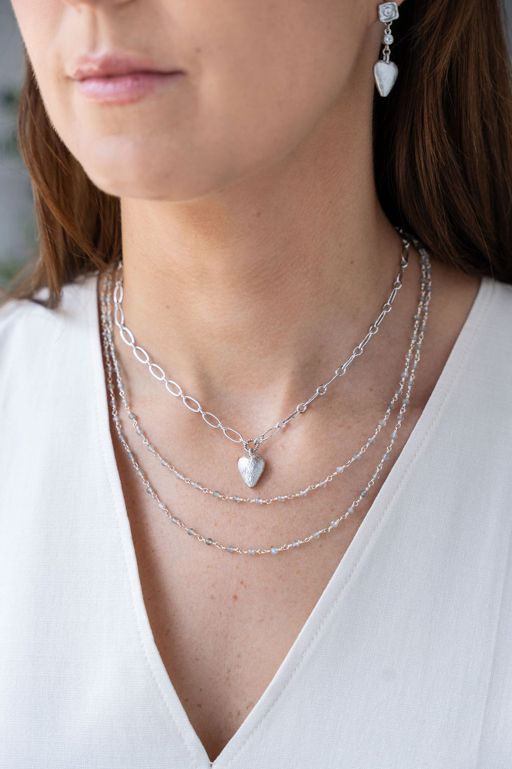 Silver heart charm necklace with elongated chain and brushed metal heart pendant