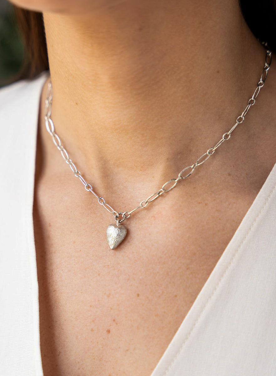 Silver heart charm necklace with elongated chain and brushed metal heart pendant