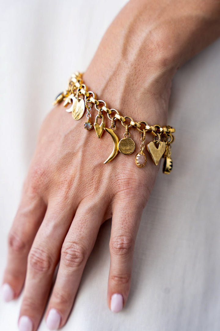 Gold charm bracelet with an eclectic mix of heart, moon, star, and gemstone charms on a chunky chain.