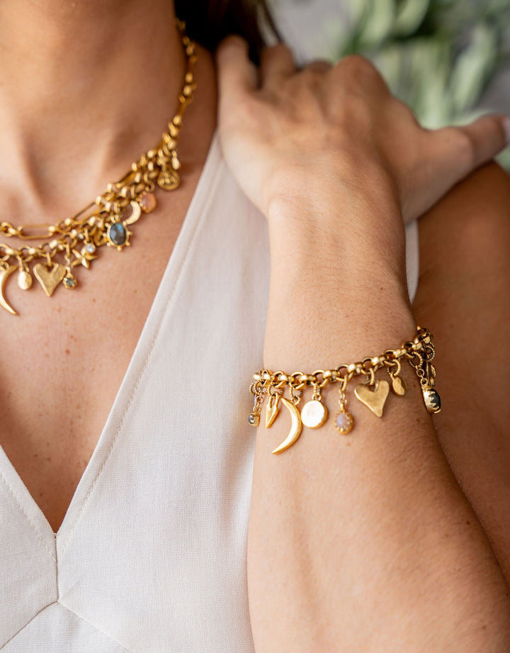 Gold charm bracelet with an eclectic mix of heart, moon, star, and gemstone charms on a chunky chain.