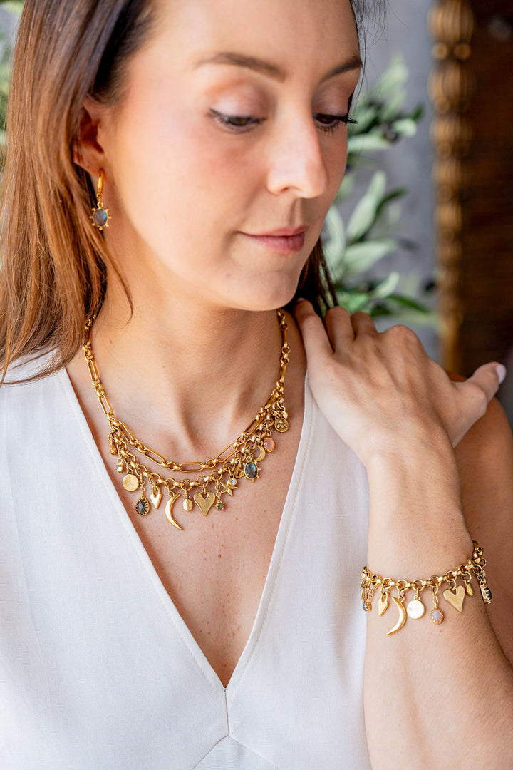 Gold charm bracelet with an eclectic mix of heart, moon, star, and gemstone charms on a chunky chain.