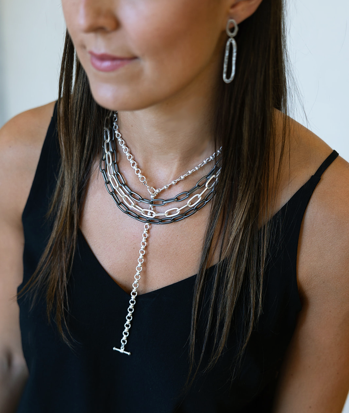A model wearing layered chainlink necklaces.