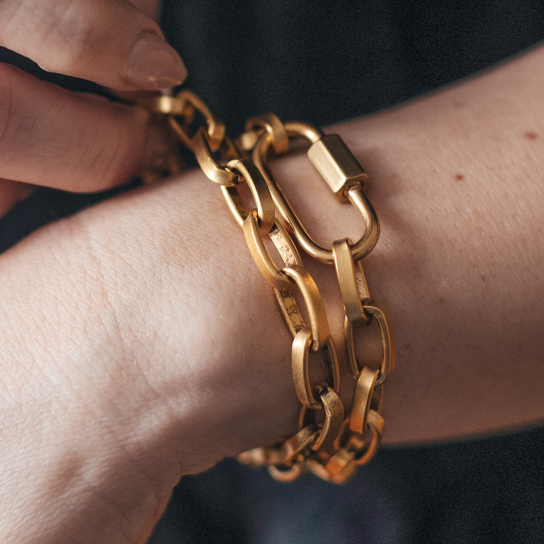 A woman's wrist modeling gold chainlink bracelets.