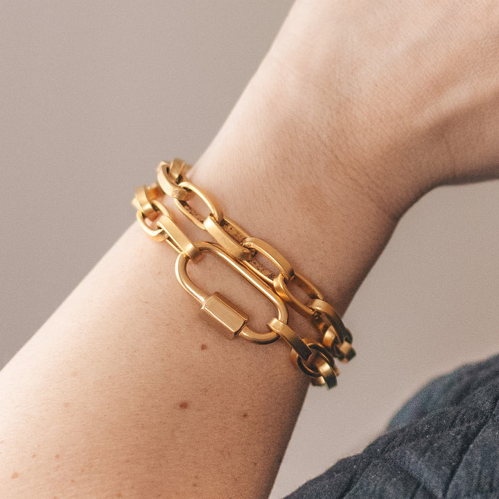 A woman's wrist modeling gold chainlink bracelets.