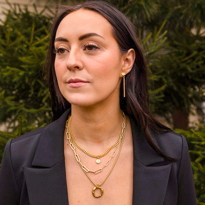 a necklace stack with three matte gold necklaces with round pendants