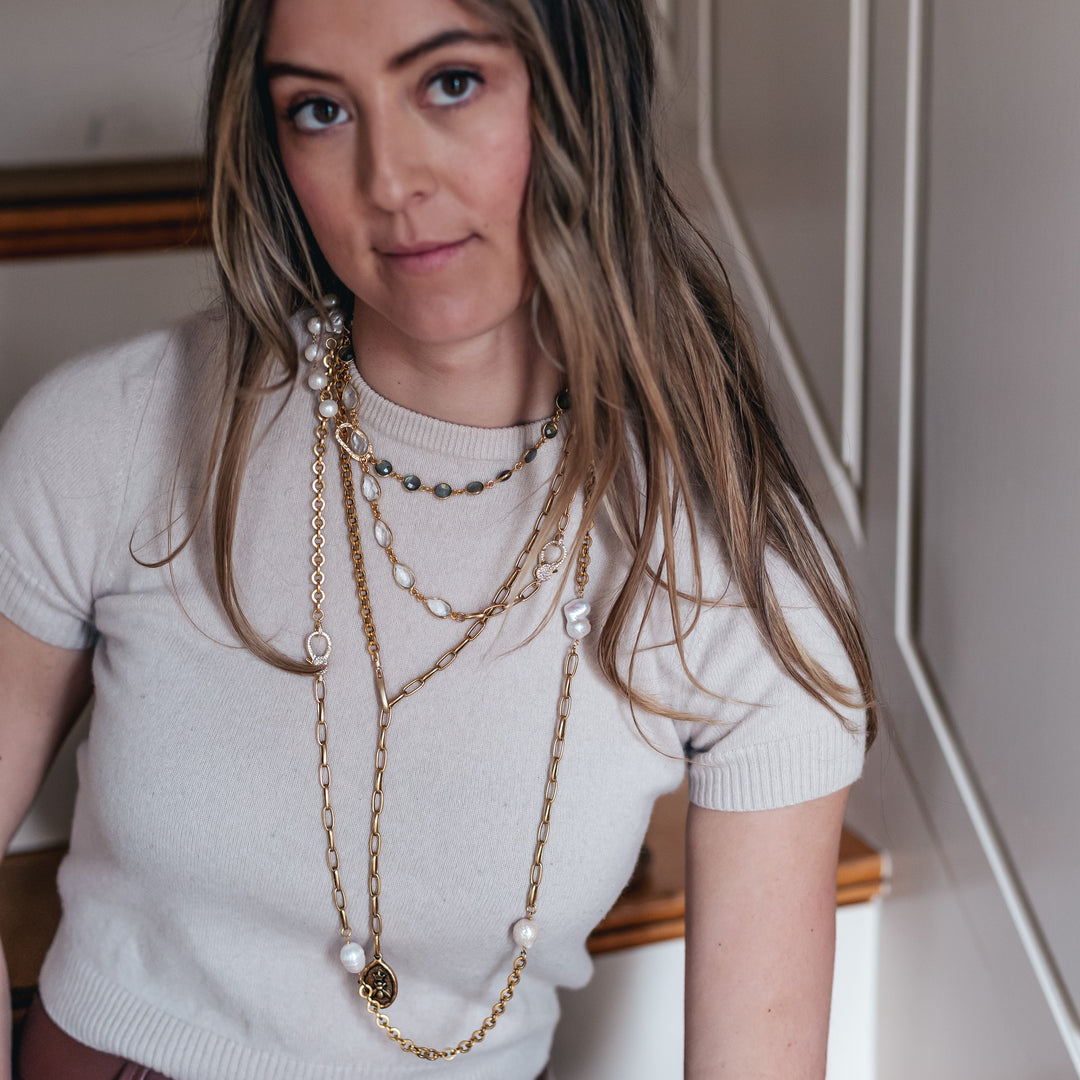 A model wearing layered chainlink and gemstone necklaces.