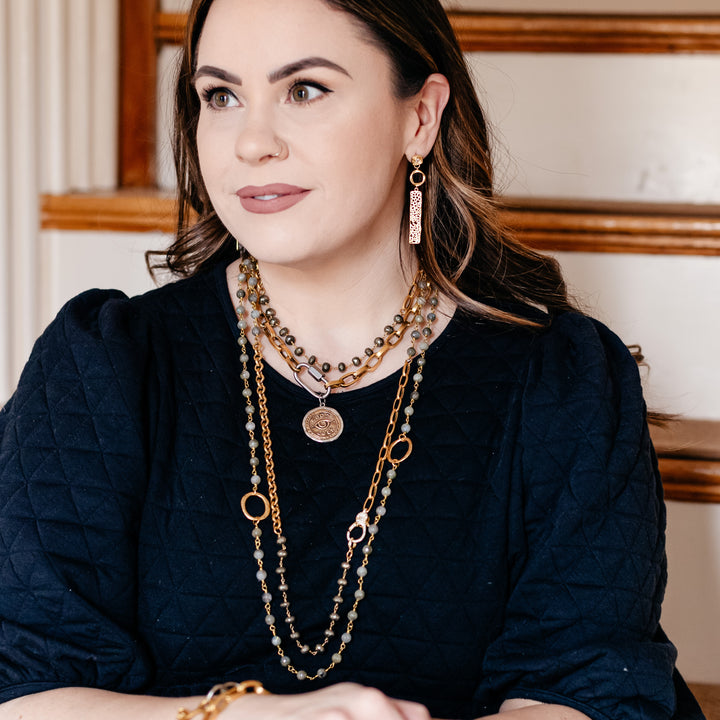 A model wearing layered chainlink and gem necklaces.