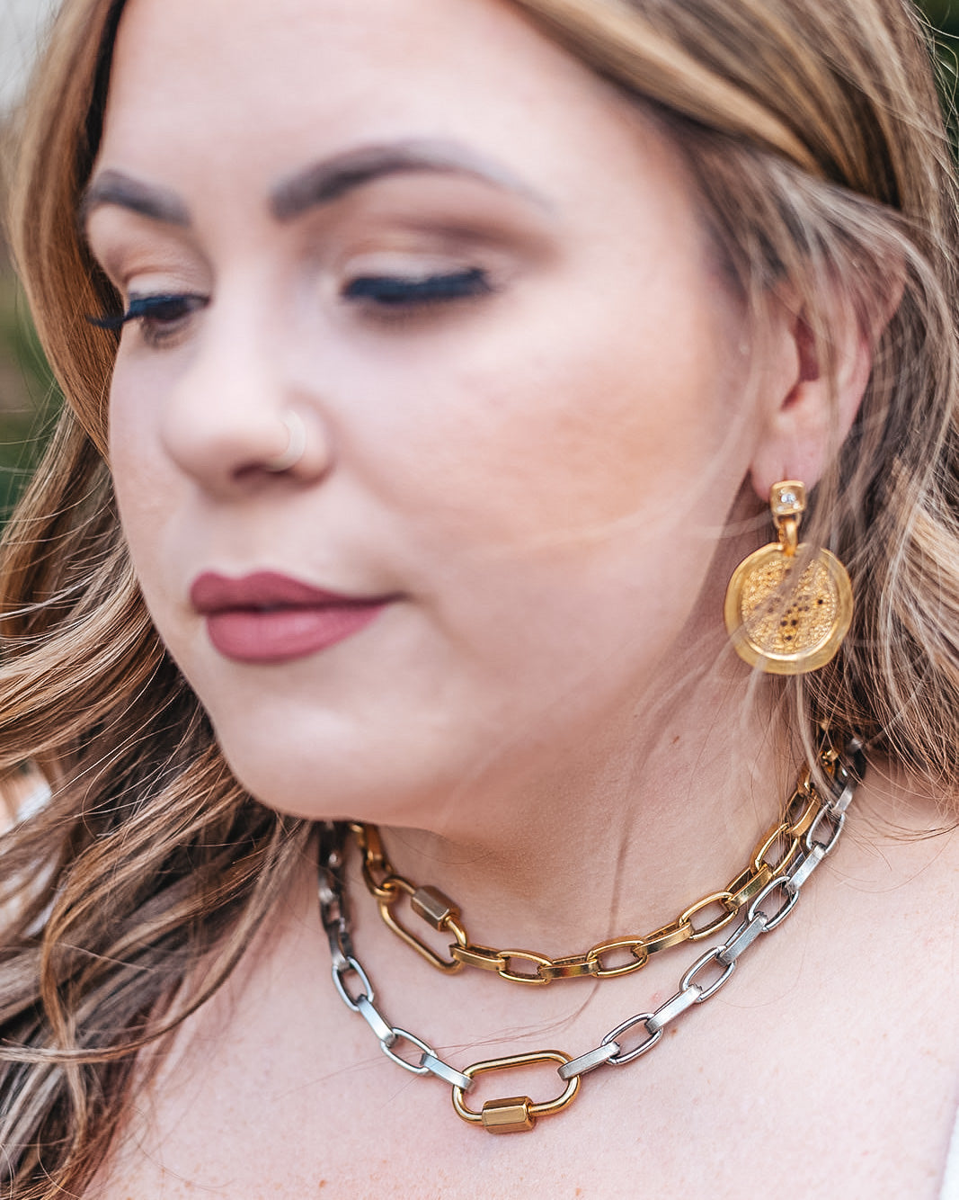 A model wearing A hammered filagree gold coin earring on a square crystal post