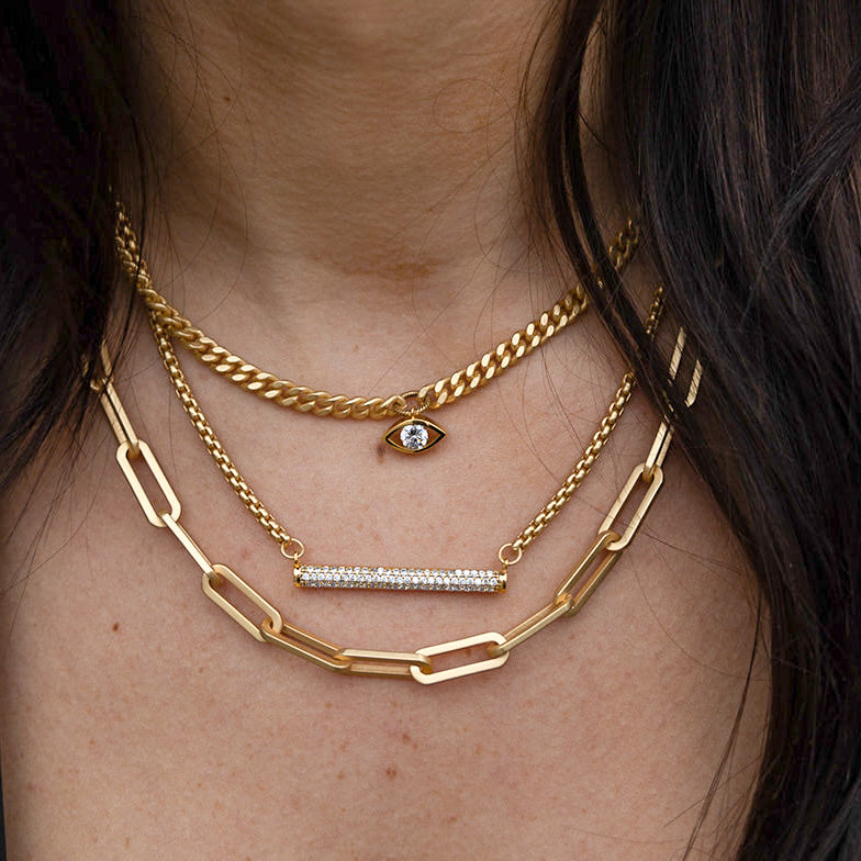 three necklaces with pave details. one with an evil eye and one with a bar.