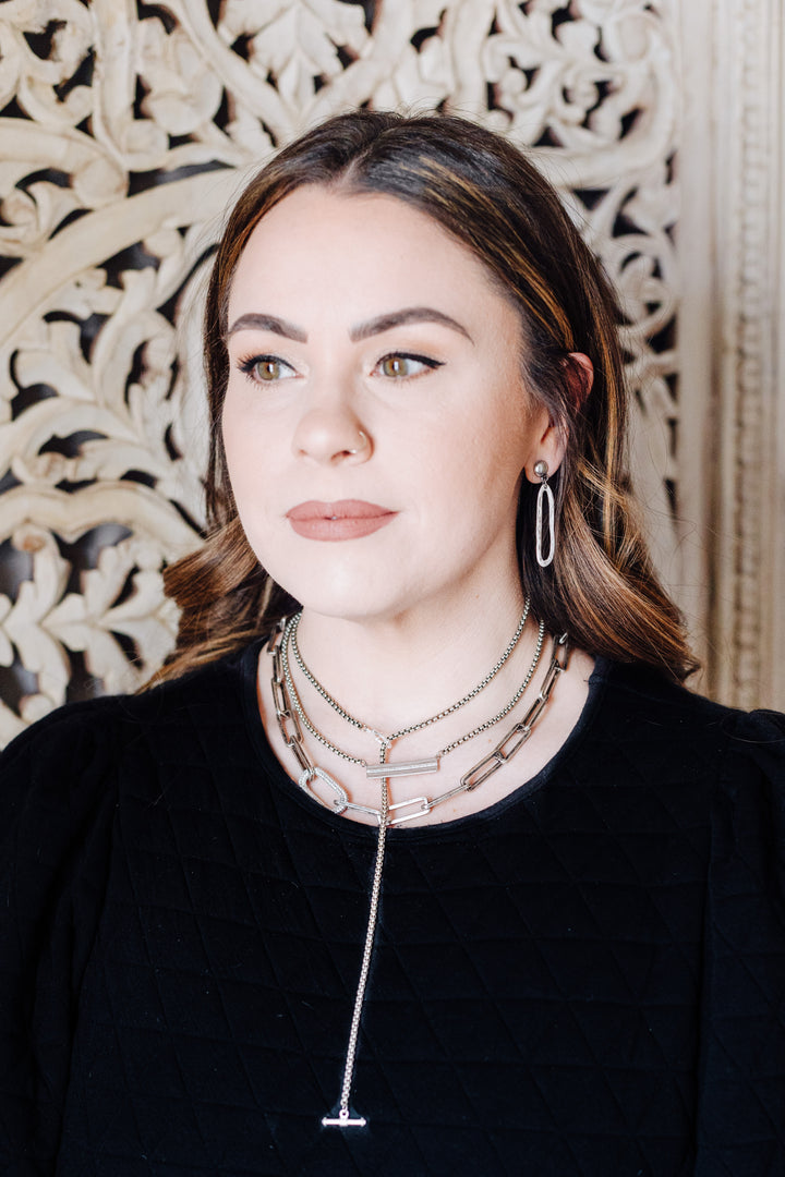 A model wearing layered silver chainlink necklaces.