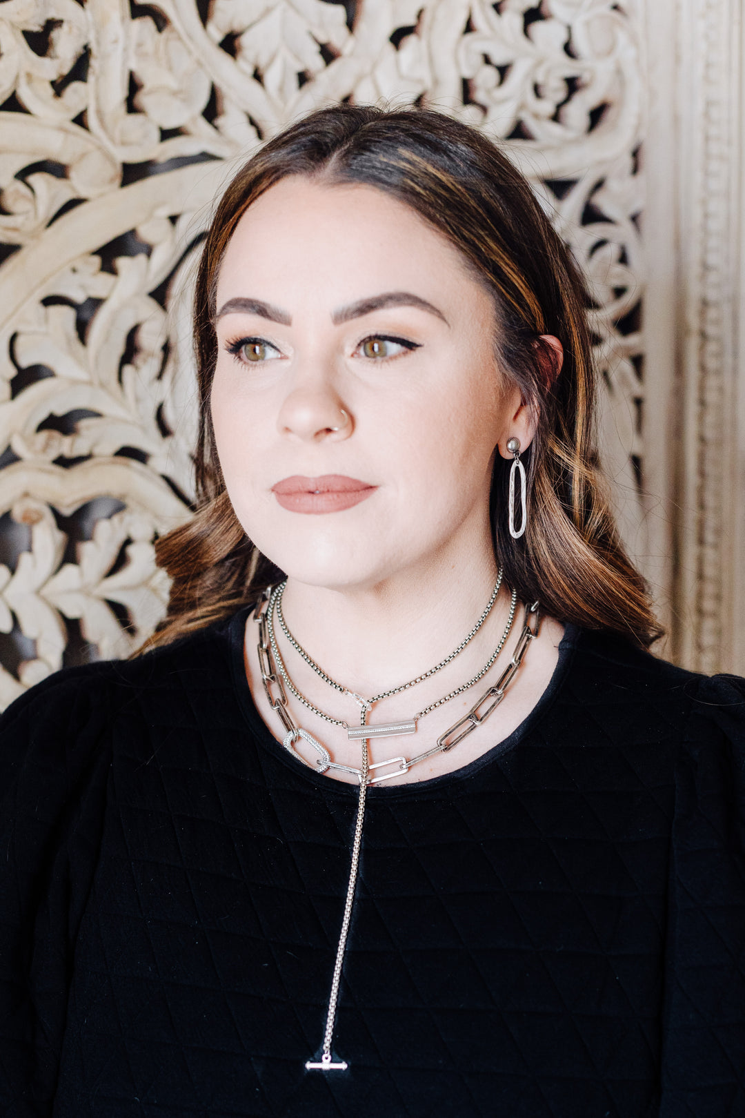 A model wearing layered silver chainlink necklaces.
