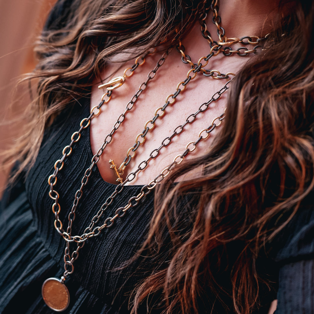 A woman modeling layered chainlink necklaces.