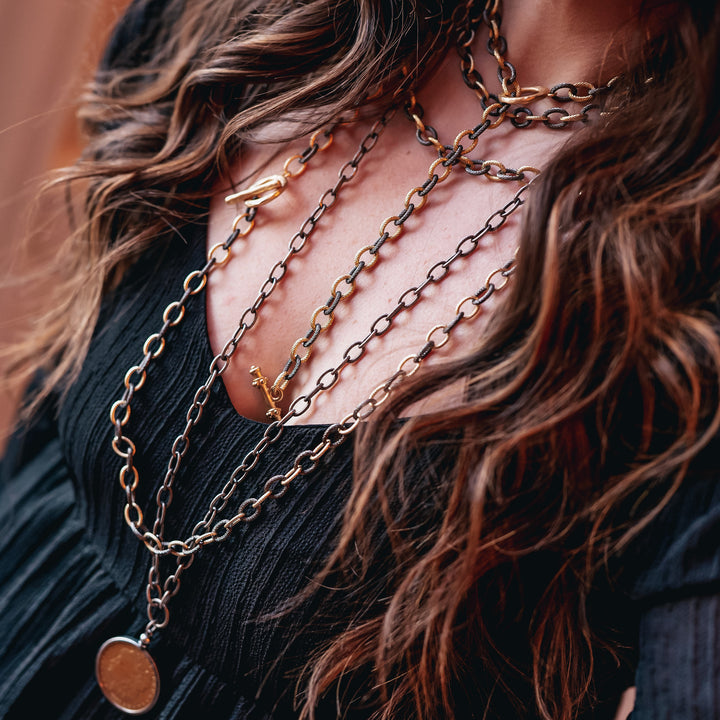 A woman modeling layered chainlink necklaces.