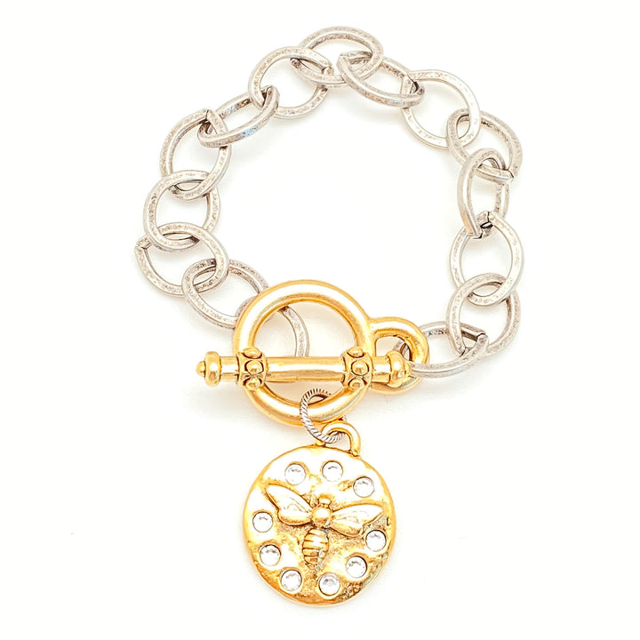 A silver chain link bracelet with a gold bee charm and toggle clasp.