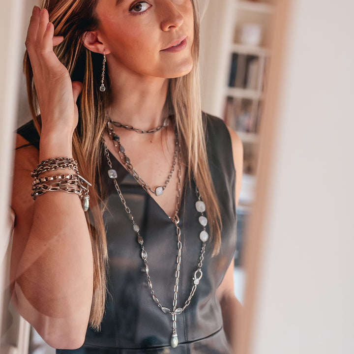 A model wearing a drop on gray crystal chain labradorite earring.