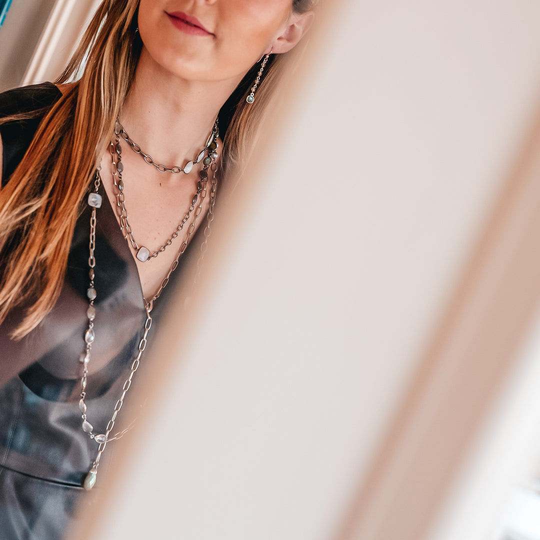 A model wearing layered chainlink and gemstone necklaces.