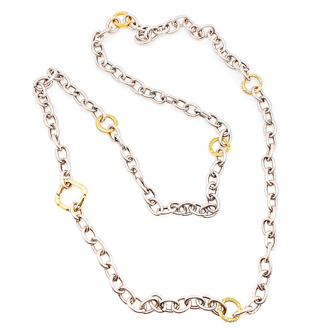 A silver layering chainlink necklace with gold accents and a square clasp.