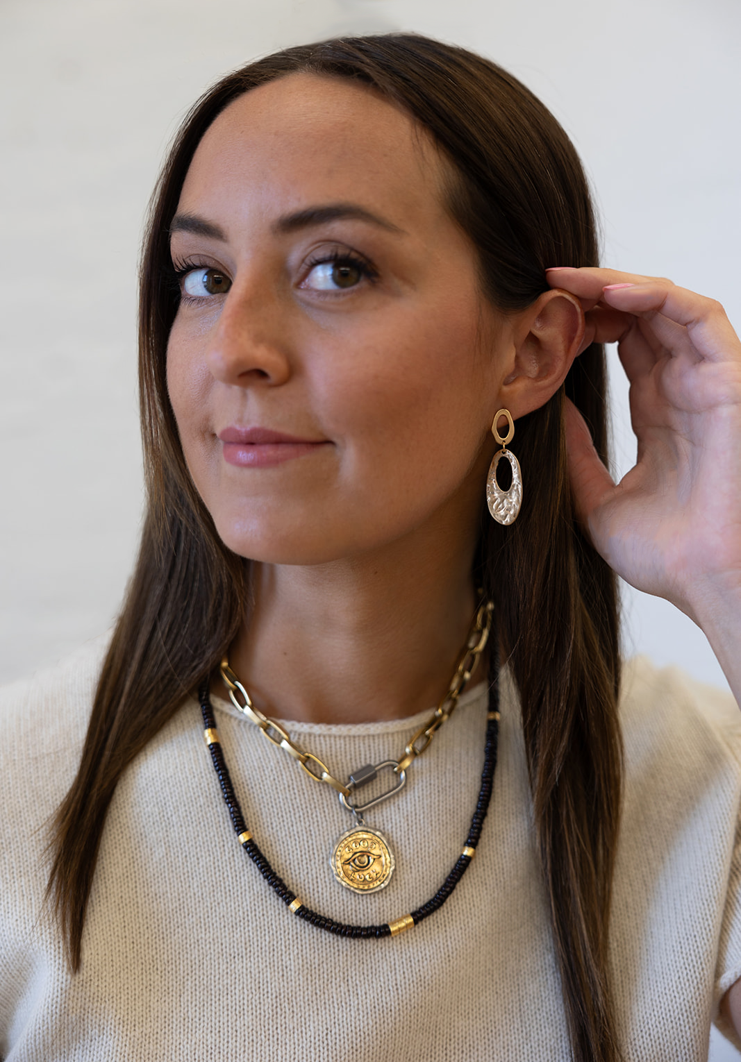 a model wearing An oval hammered dangle earring on oval cutout posts.