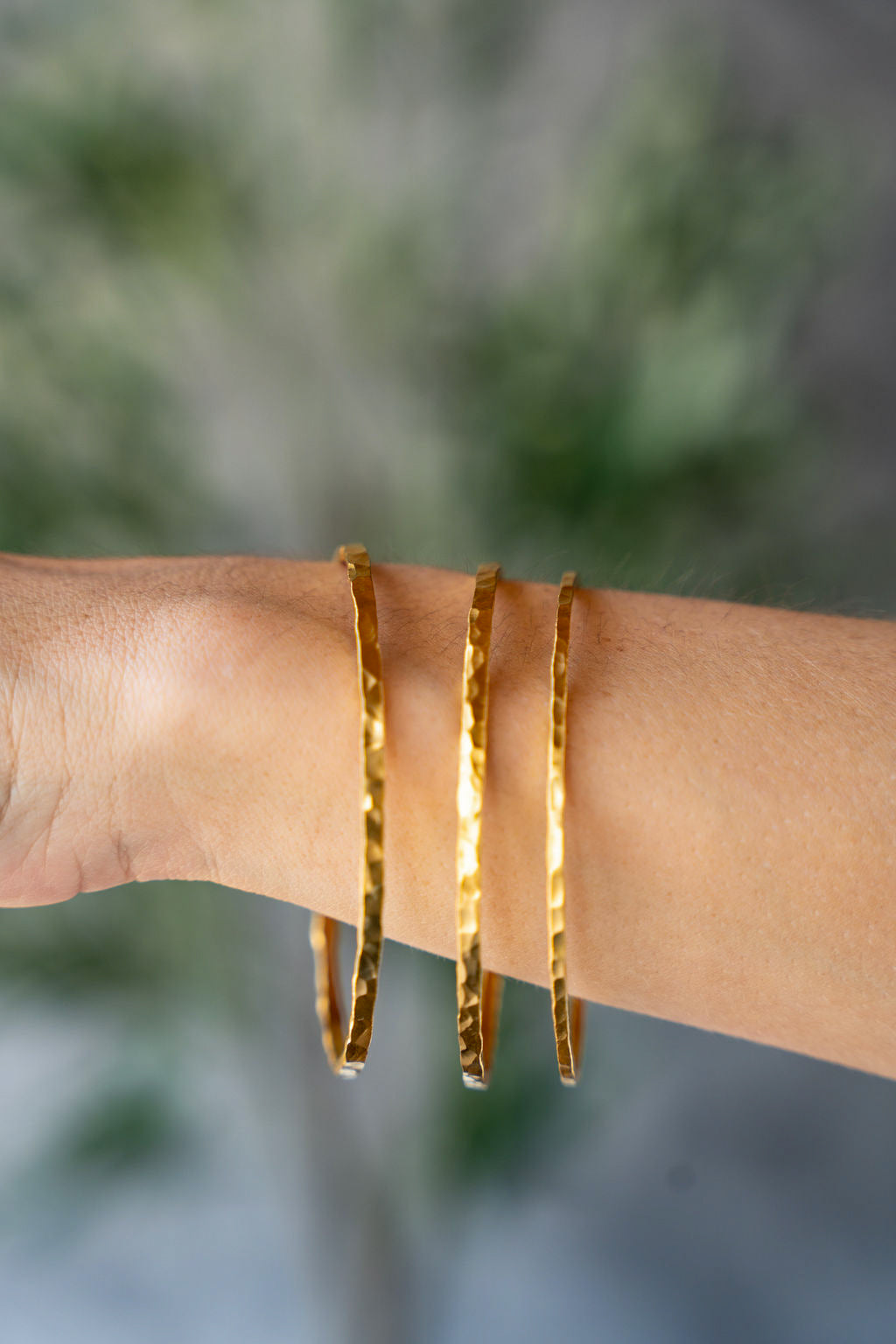Wide hammered gold bangle bracelet with organic hand-forged texture.