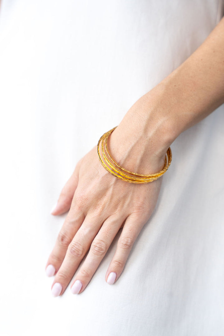 Wide hammered gold bangle bracelet with organic hand-forged texture.