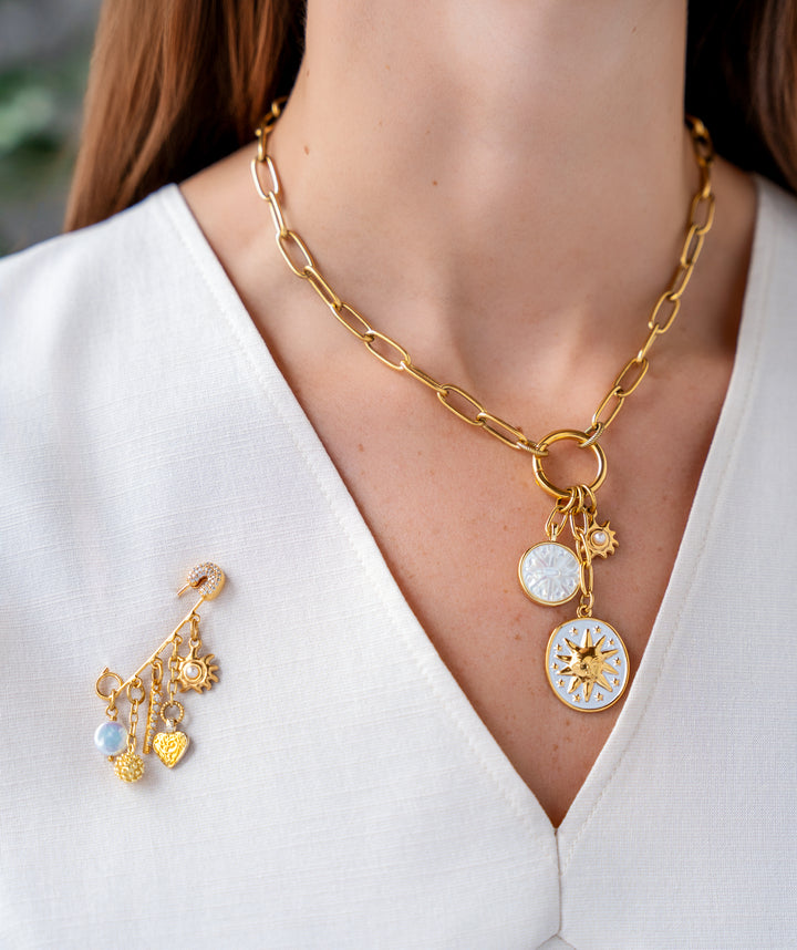 Gold paperclip chain necklace with enamel celestial charms, mother-of-pearl detail, and a sun medallion pendant.