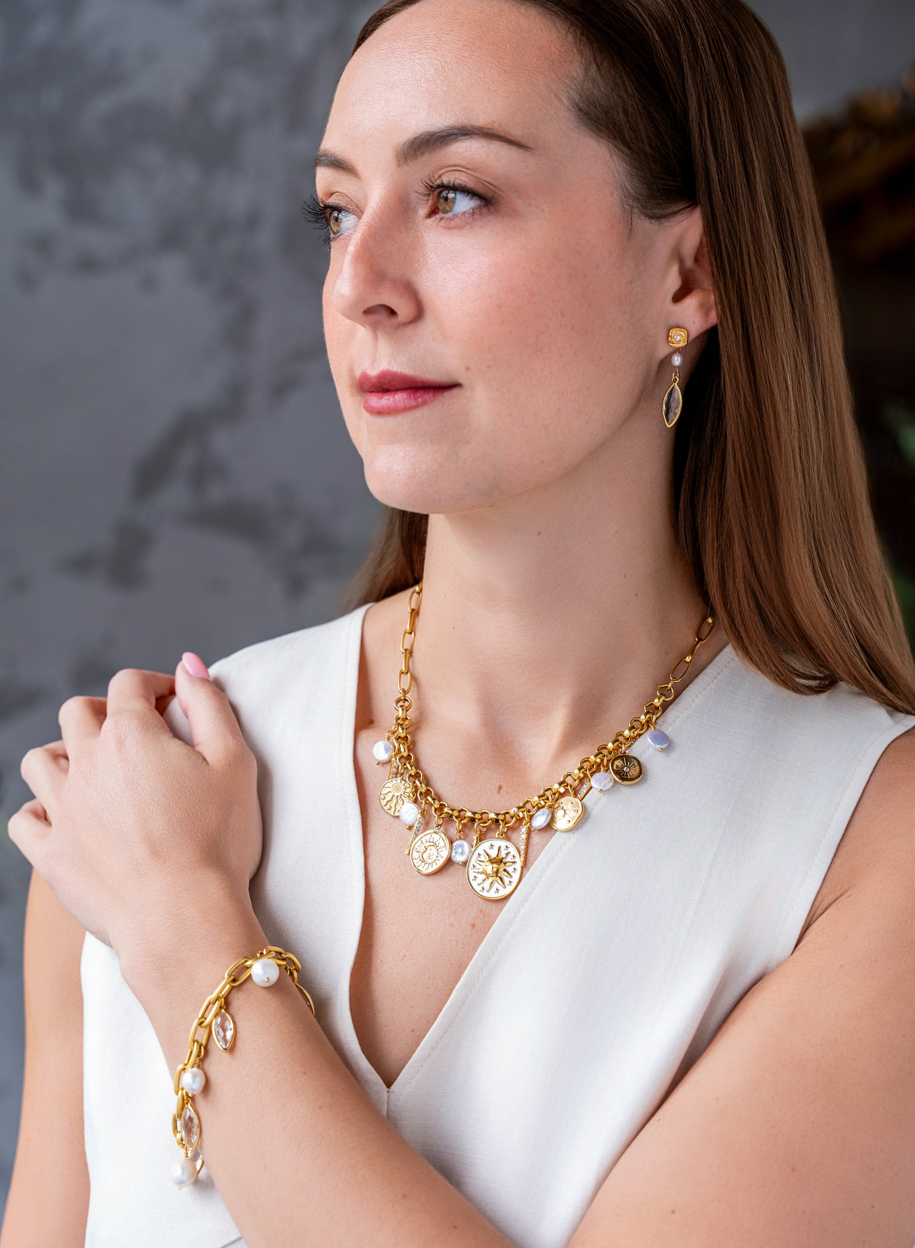 Gold celestial charm necklace with sun medallions, coin pearls, pavé crystal accents, and dangling celestial charms on a chunky chain.