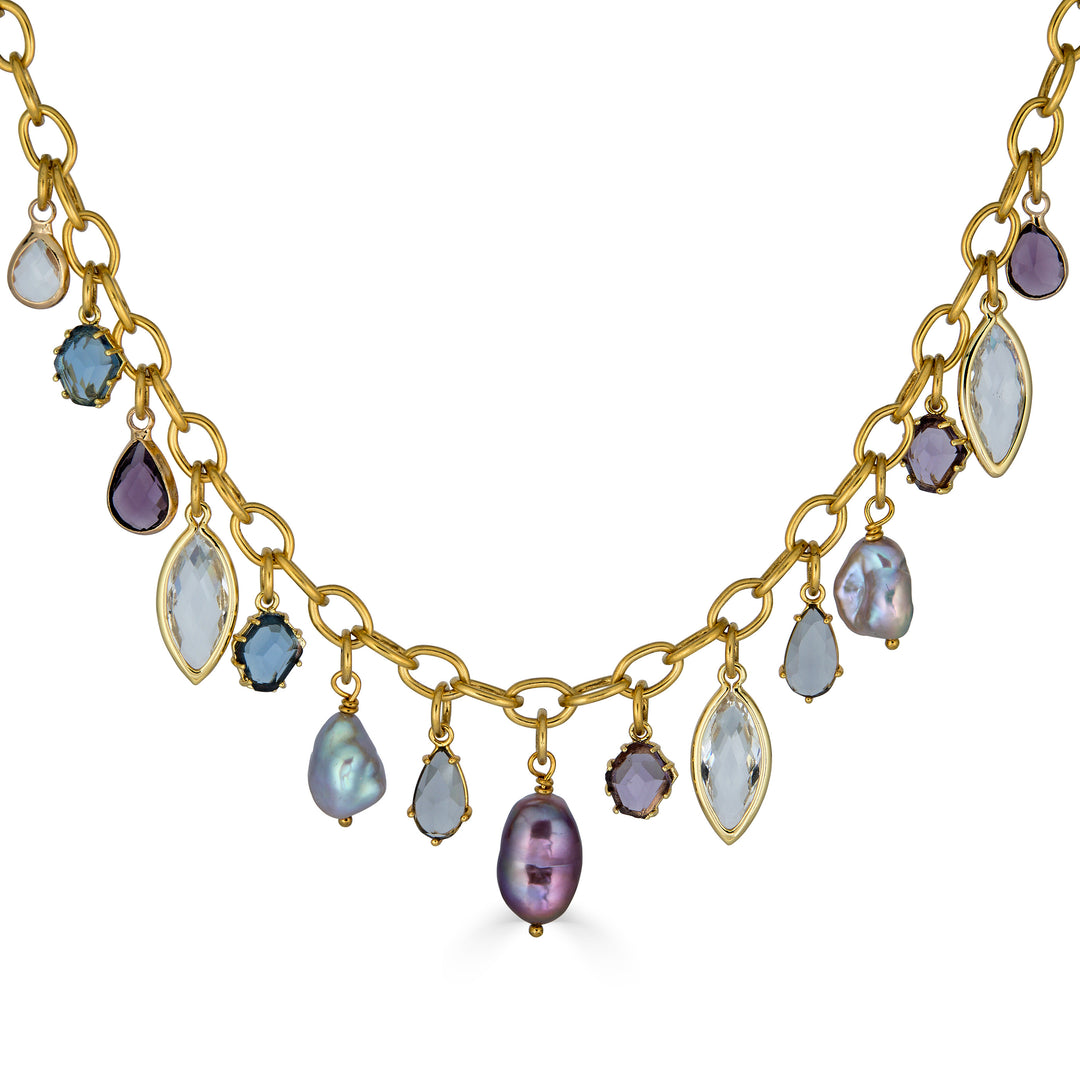 Gold charm necklace with colorful faceted gemstone charms and freshwater pearls dangling from an elongated gold chain.