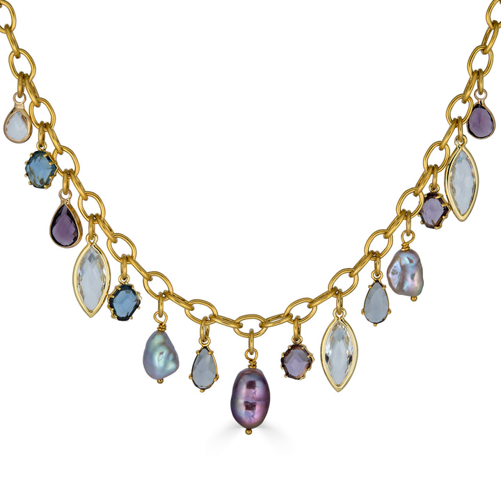 Gold charm necklace with colorful faceted gemstone charms and freshwater pearls dangling from an elongated gold chain.