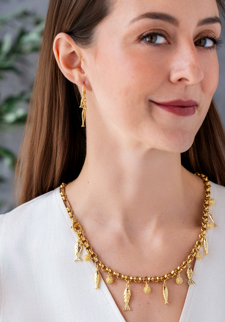 Convertible gold fish charm necklace with dangling fish and textured bead charms worn as both a lariat and classic chain necklace.