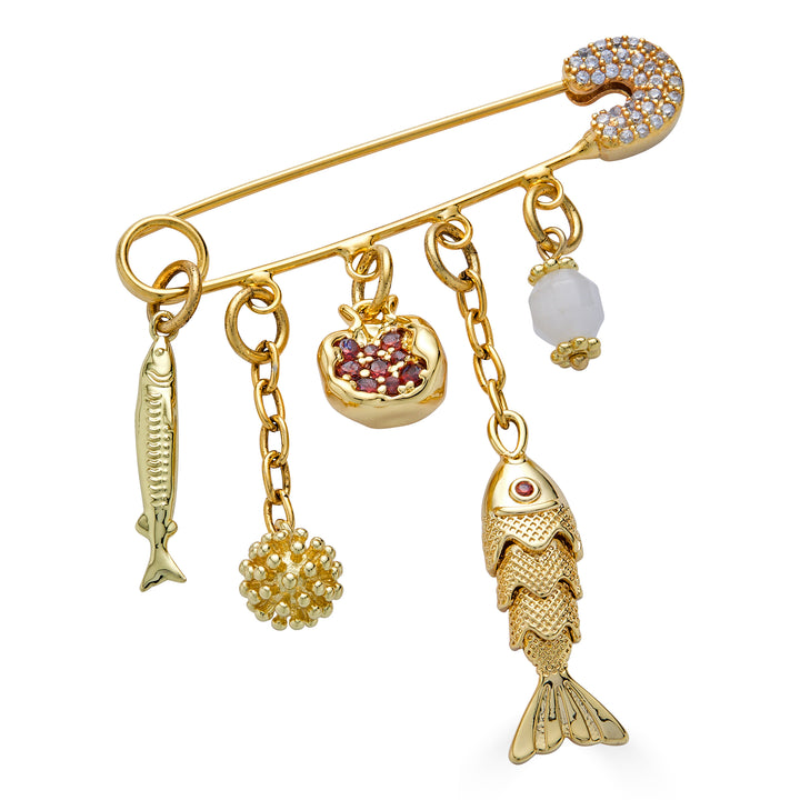 Gold charm brooch with fish charms, pomegranate charm, and dangling textured accents.