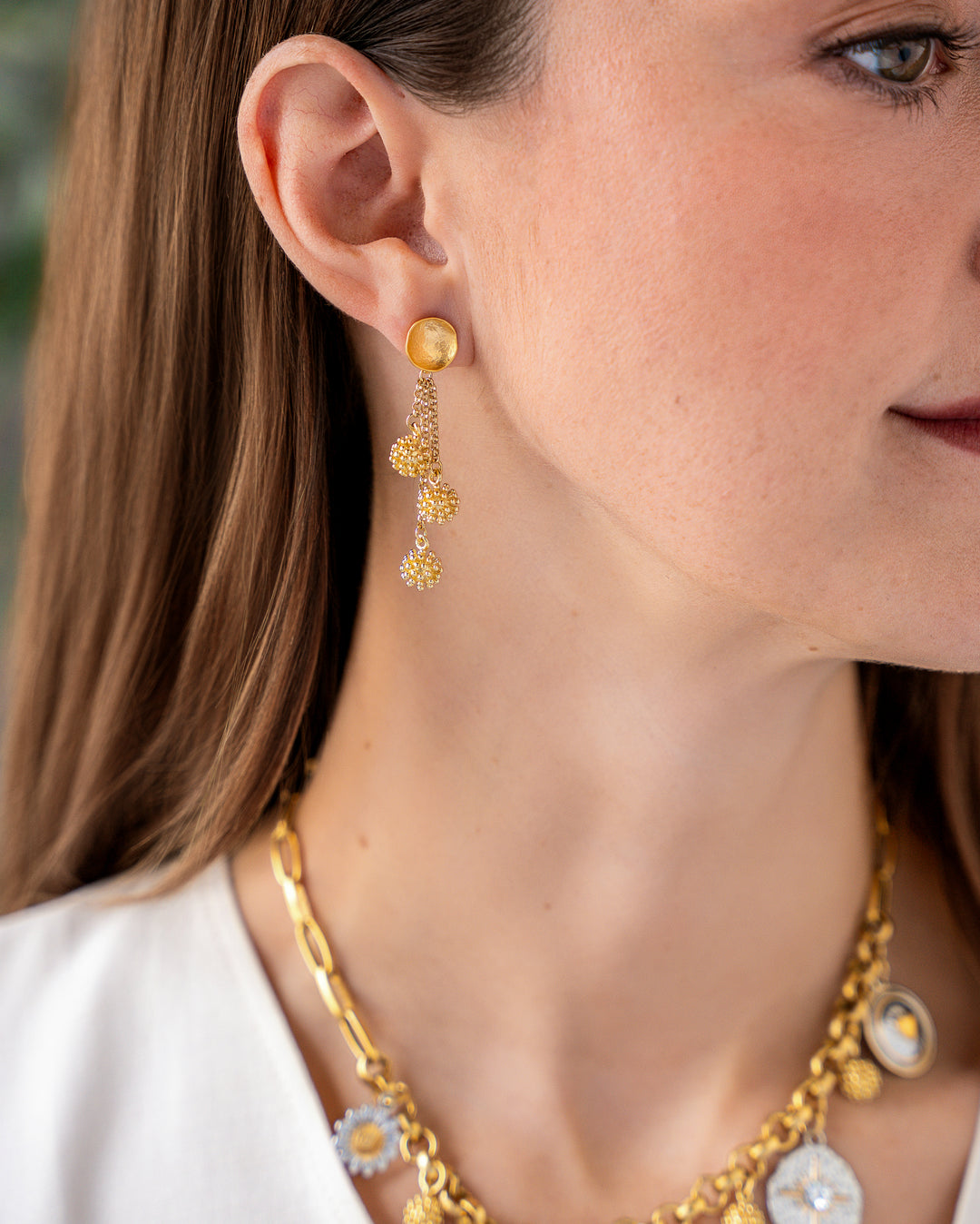 Gold drop earrings with hammered disc tops, cascading chains, and textured cluster bead charms.